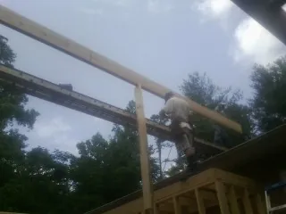 Carpenter setting a ridge beam over a new addition frame — Ice Dam Removal by Roofing Brothers in Danese