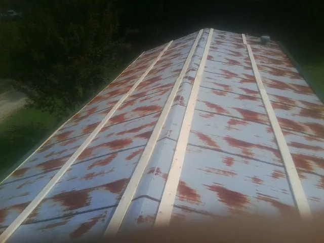 Rusted metal roof panels with new wood purlins before replacement — Storm Damage Roof Repair in Danese by Roofing Brothers