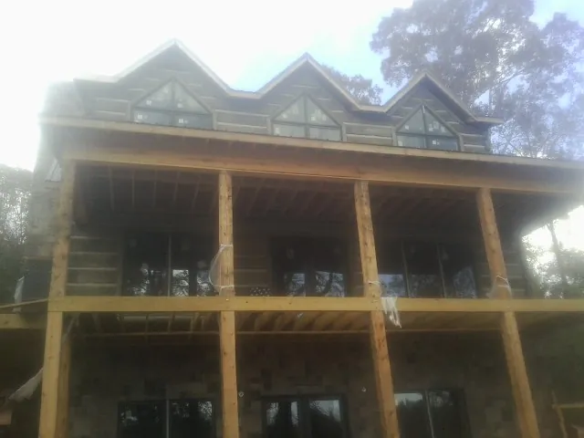 Dormers and porch framing on a large log home under construction — Roof Coating work by our crew in Danese