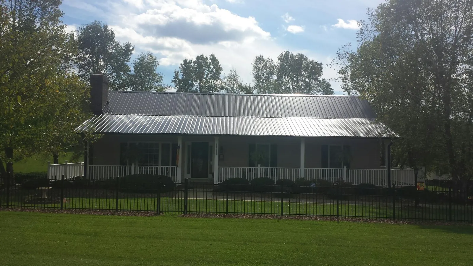 Gray metal roof on a brick ranch with a full width front porch — Gutter Guard Installation work by our crew in Danese