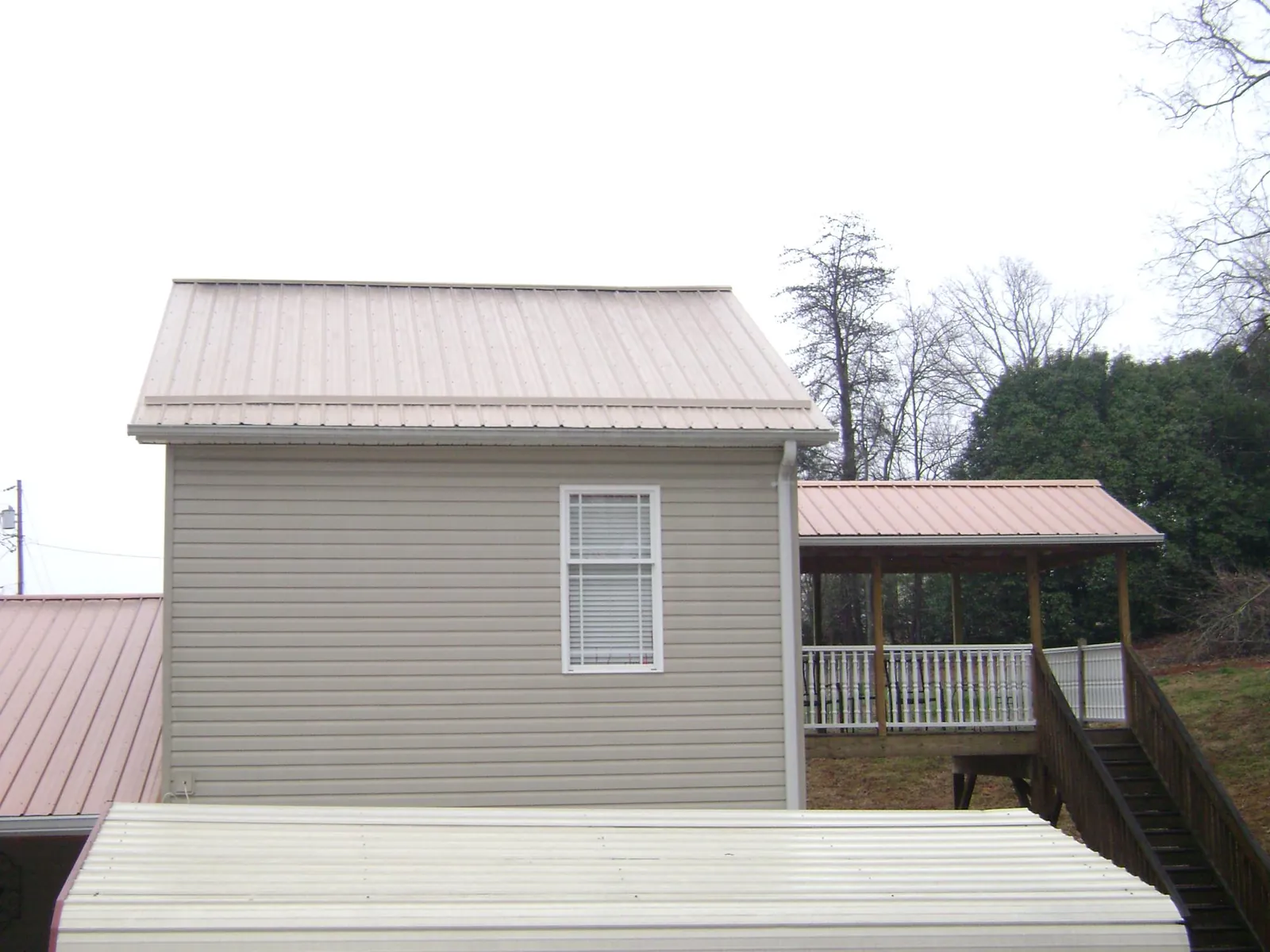 Tan metal roofs on a two story addition and attached porch, from a Roof Replacement job in Danese