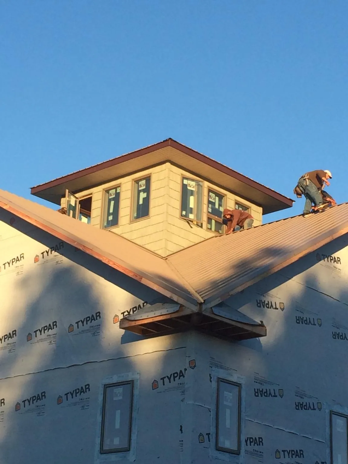 Roofers working around a rooftop cupola on a new metal roof at sunset — Roof Waterproofing in Danese by Roofing Brothers